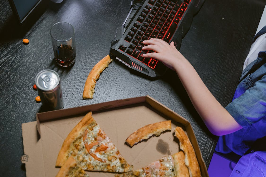 top view of a gaming desk with pizza and drinks