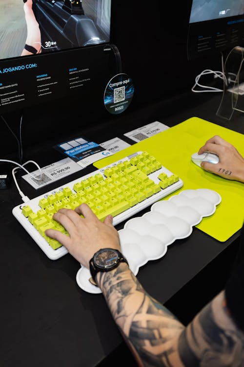 Person sitting down on PC setup with white keyboard and mouse with neon green mouse pad and keycaps